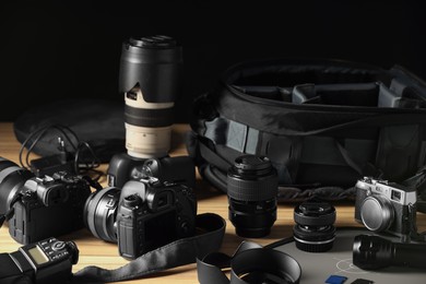 Photo of Professional photographer's equipment and backpack on wooden table