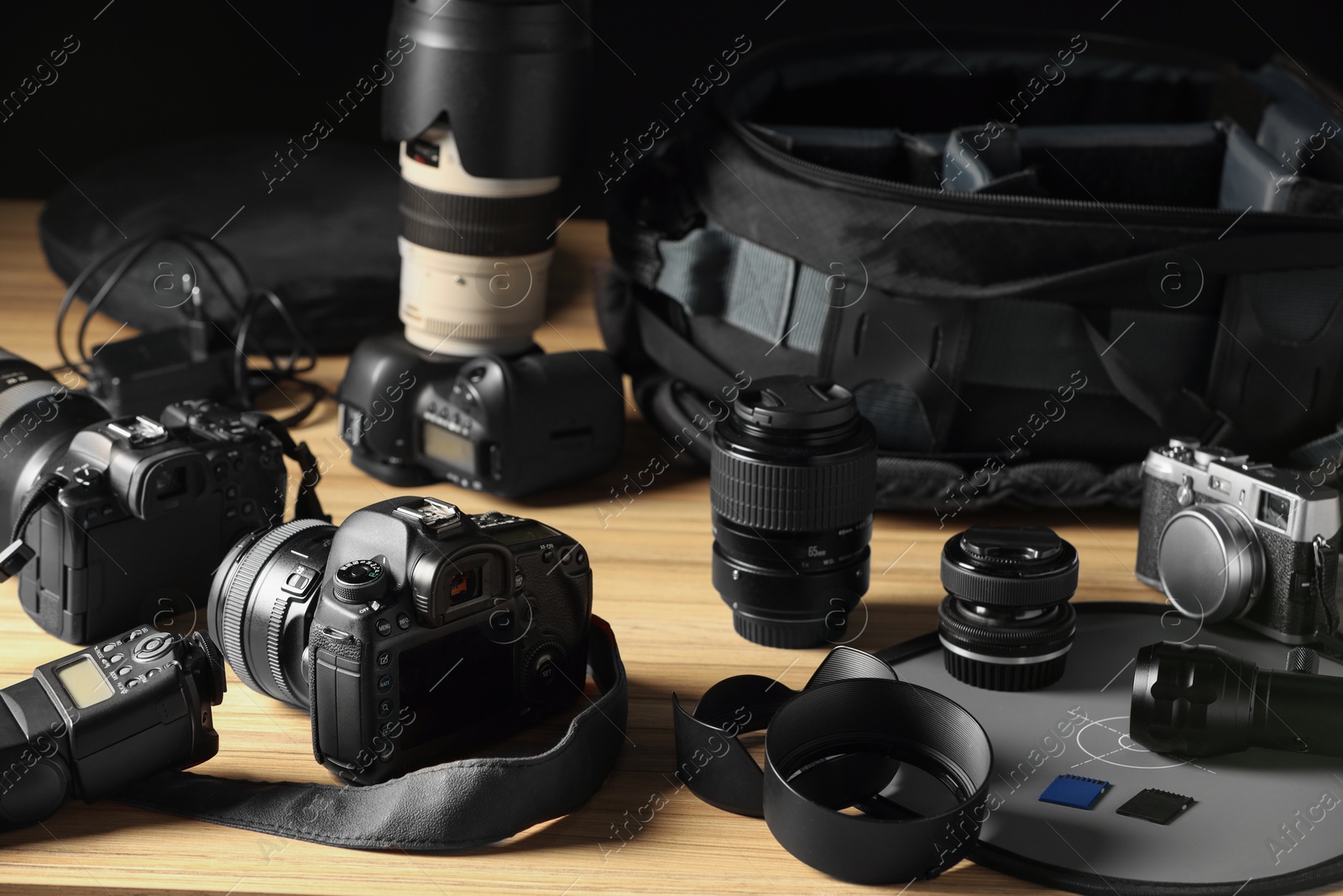 Photo of Professional photographer's equipment and backpack on wooden table