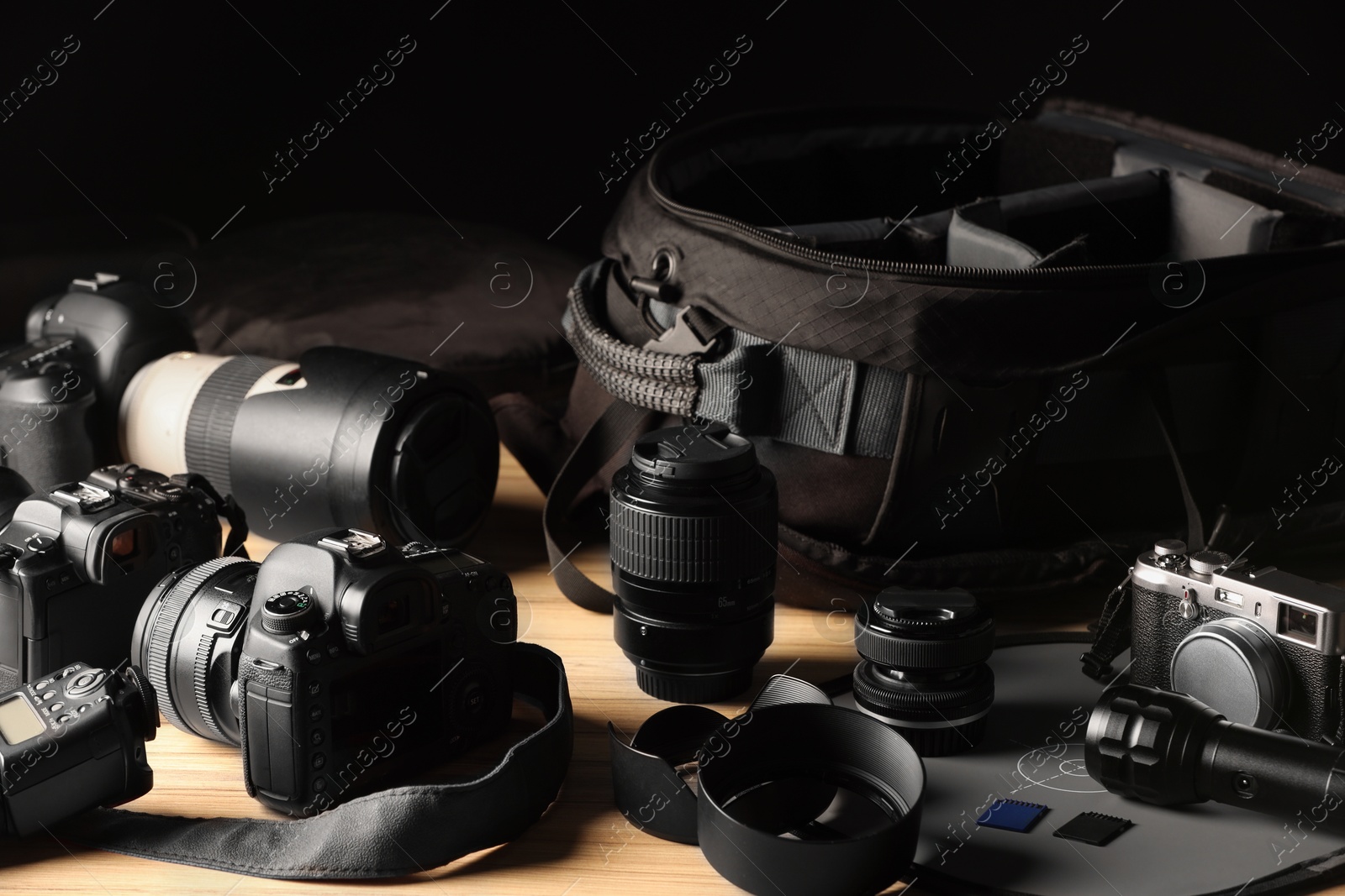 Photo of Professional photographer's equipment and backpack on wooden table