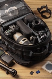 Professional photographer's equipment and backpack on wooden table