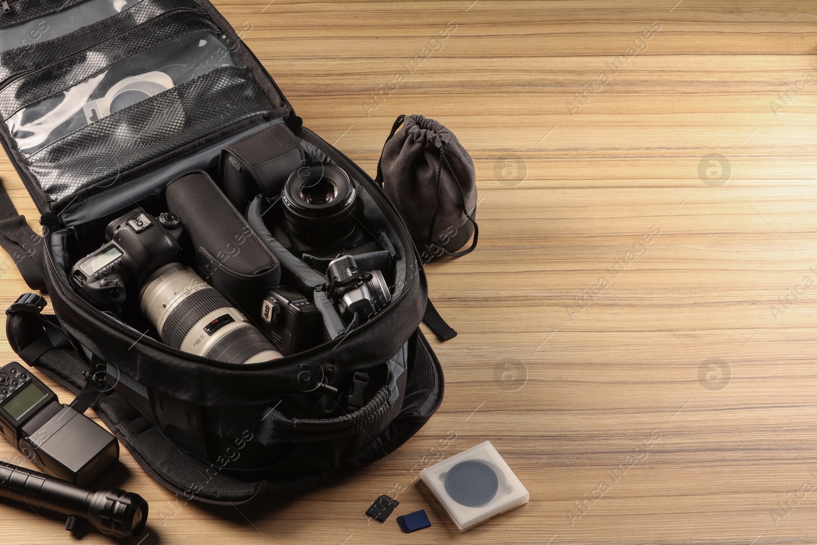 Photo of Professional photographer's equipment and backpack on wooden table. Space for text