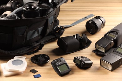 Photo of Professional photographer's equipment and backpack on wooden table