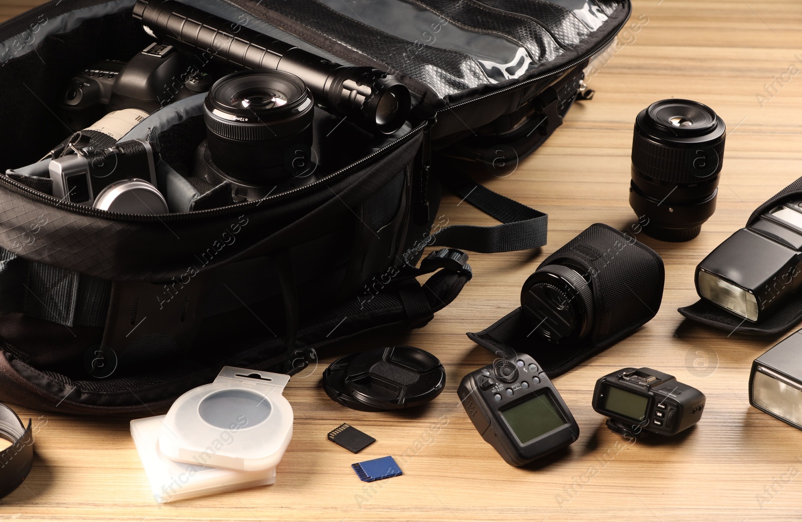 Photo of Professional photographer's equipment and backpack on wooden table