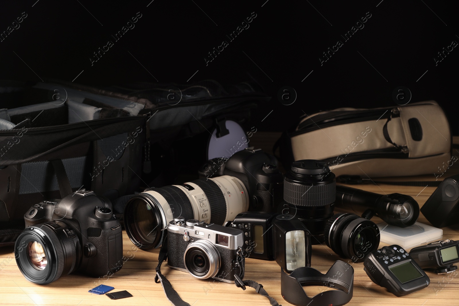 Photo of Professional photographer's equipment and backpack on wooden table