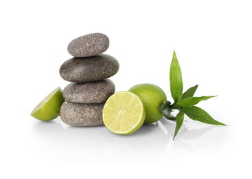 Photo of Spa composition with fresh limes, stack of pebble stones and bamboo leaves on mirror surface against white background