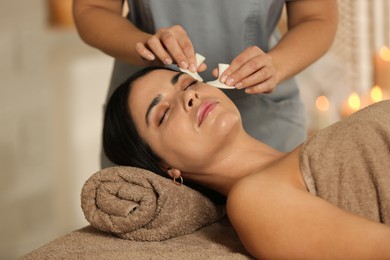 Photo of Young woman receiving facial massage with spa stones in salon