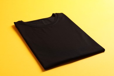 Photo of Blank black t-shirt on yellow background. Mockup for design