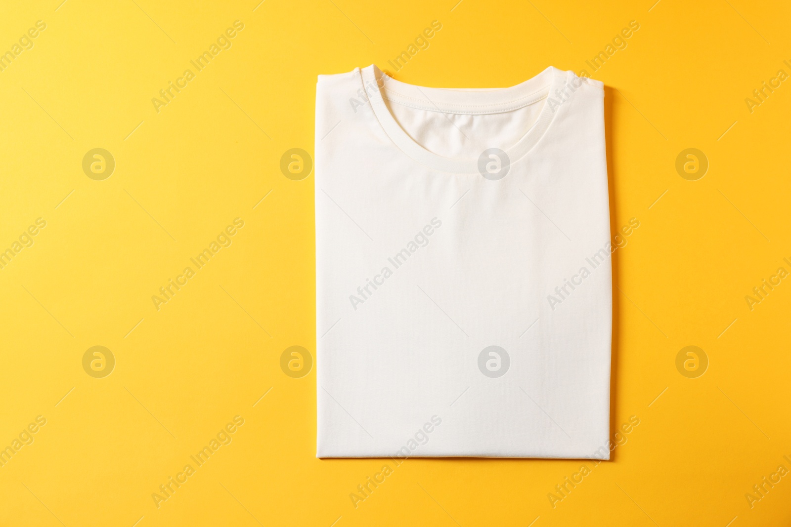 Photo of Blank white t-shirt on yellow background, top view. Mockup for design