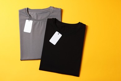 Photo of Different blank t-shirts on yellow background, top view. Mockup for design