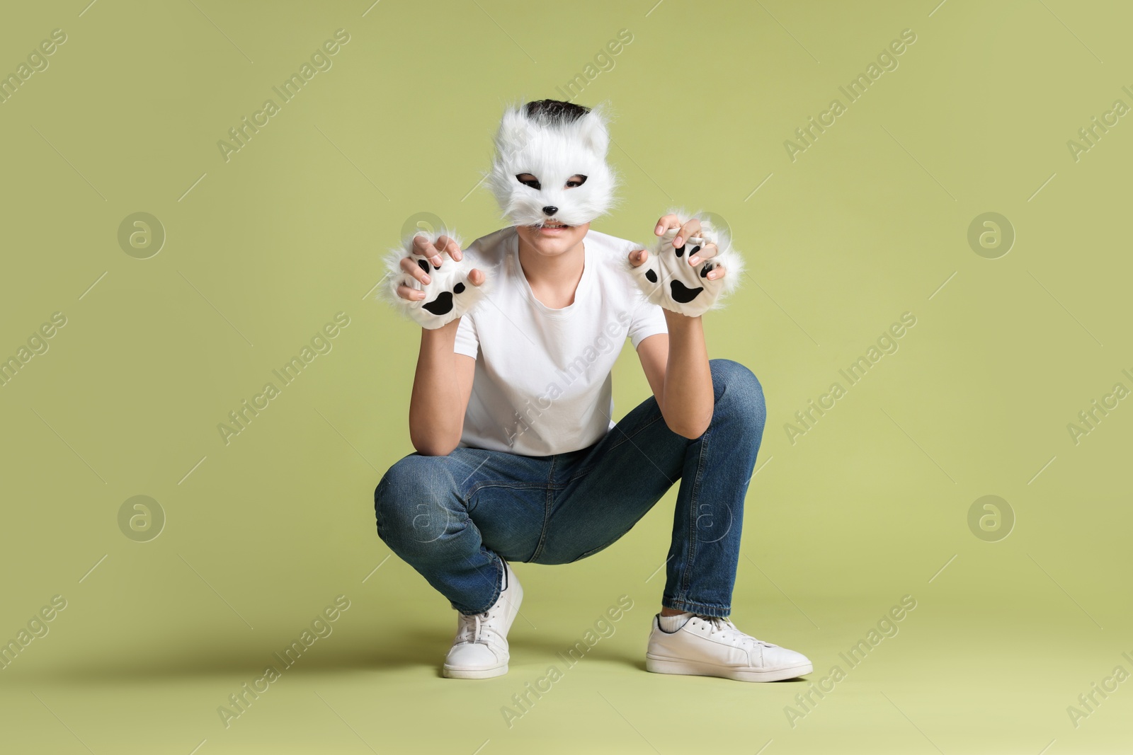 Photo of Quadrobics. Boy wearing cat mask and gloves on pale olive background