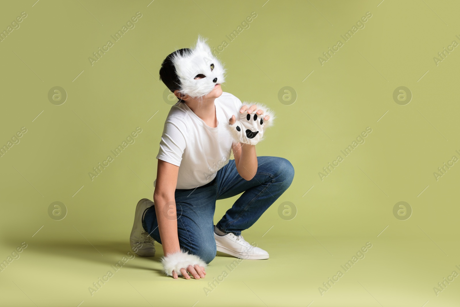 Photo of Quadrobics. Boy wearing cat mask and gloves on pale olive background