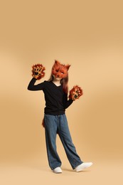 Photo of Quadrobics. Girl wearing fox mask, tail and gloves on beige background