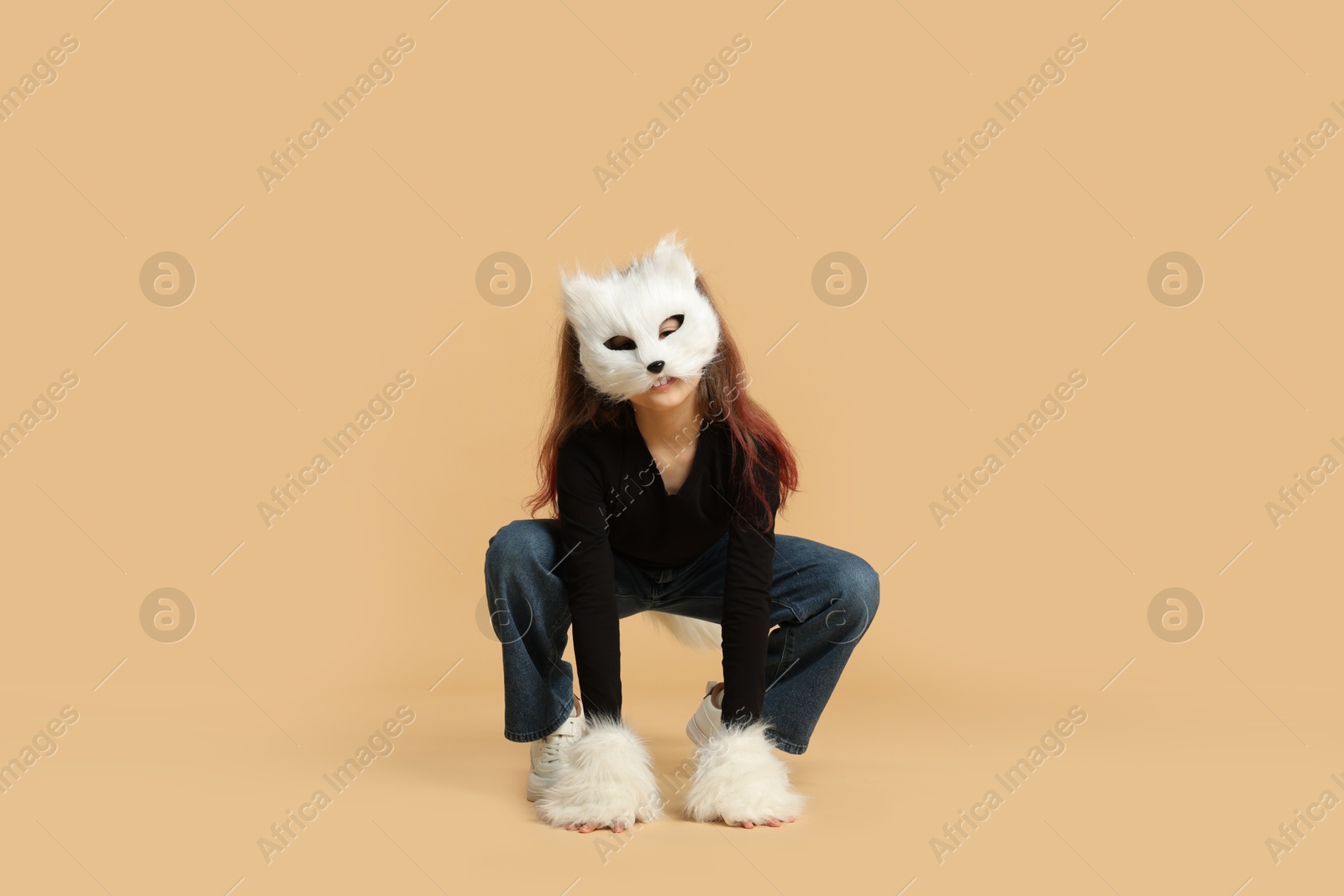 Photo of Quadrobics. Girl wearing cat mask and gloves on beige background