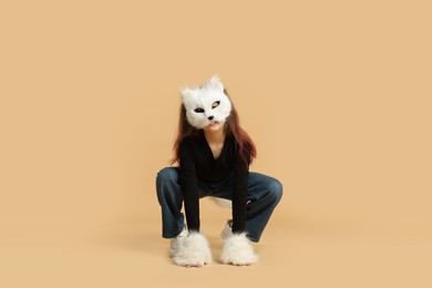 Photo of Quadrobics. Girl wearing cat mask and gloves on beige background