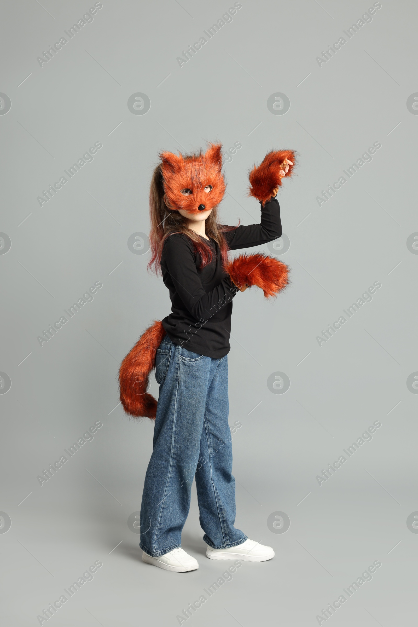 Photo of Quadrobics. Girl wearing fox mask, tail and gloves on grey background