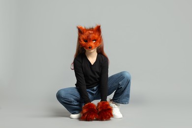 Photo of Quadrobics. Girl wearing fox mask and gloves on grey background