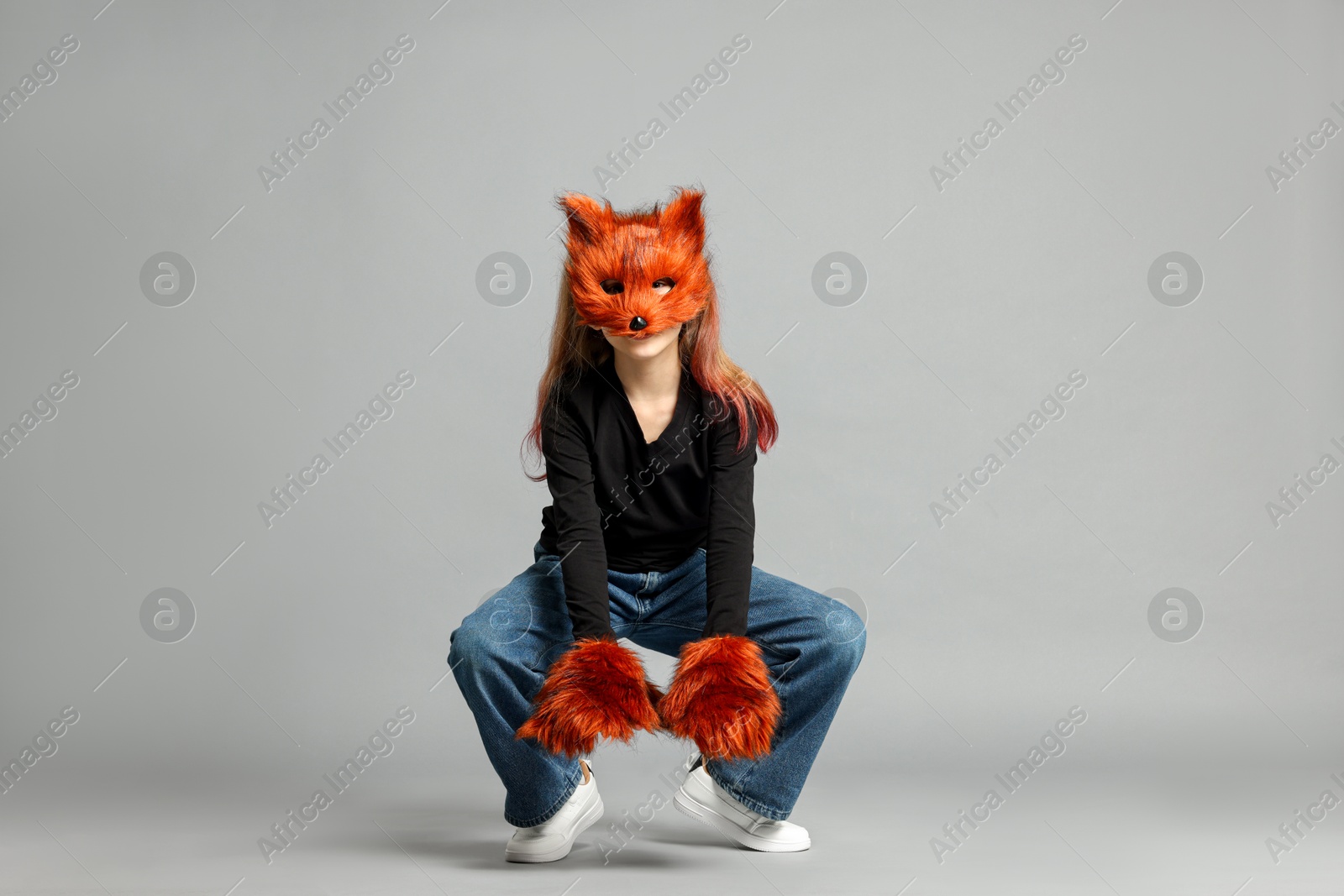 Photo of Quadrobics. Girl wearing fox mask and gloves on grey background