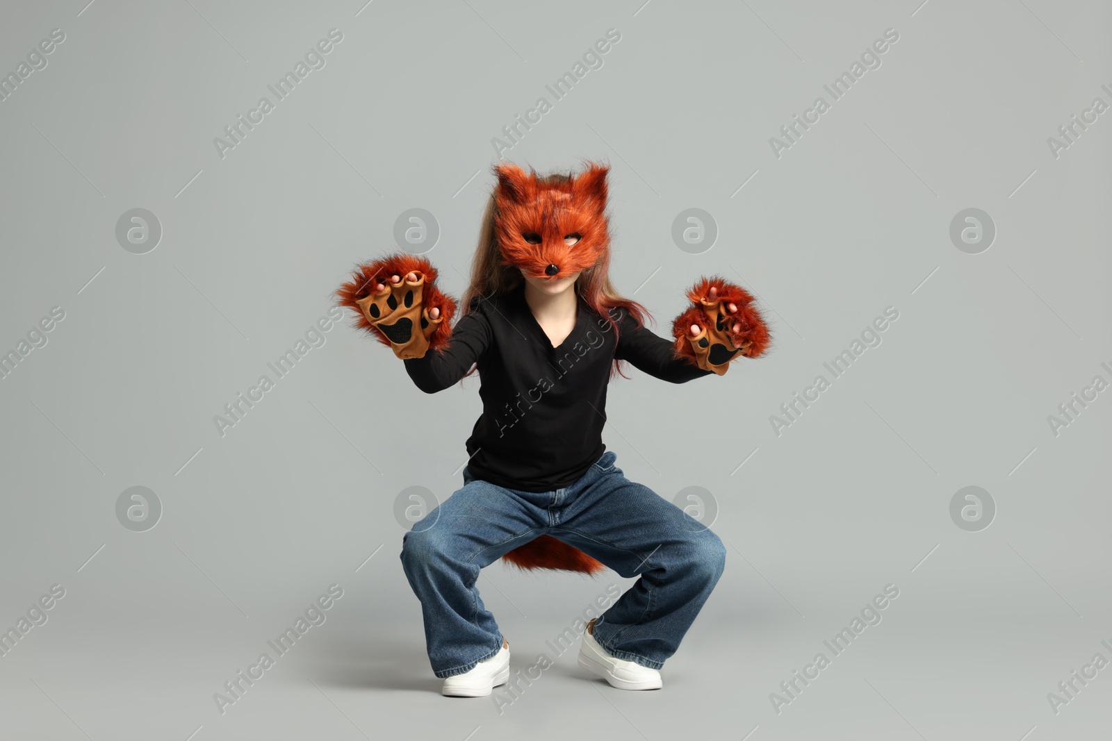 Photo of Quadrobics. Girl wearing fox mask, tail and gloves on grey background