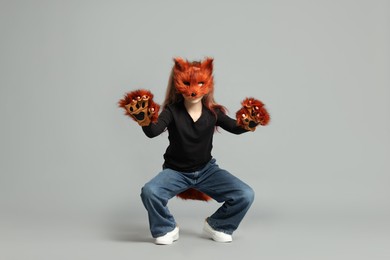 Photo of Quadrobics. Girl wearing fox mask, tail and gloves on grey background