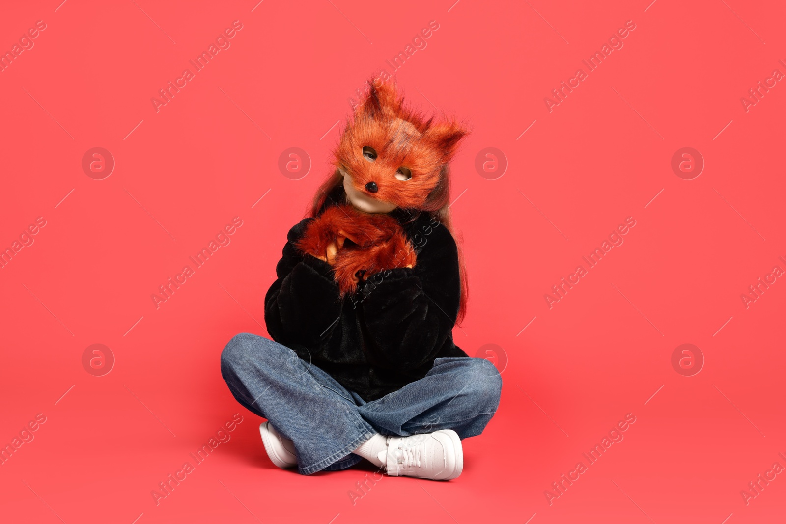 Photo of Quadrobics. Girl wearing fox mask and gloves on red background