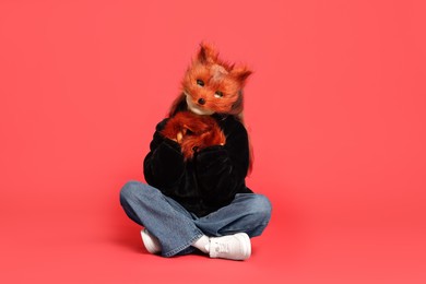 Photo of Quadrobics. Girl wearing fox mask and gloves on red background