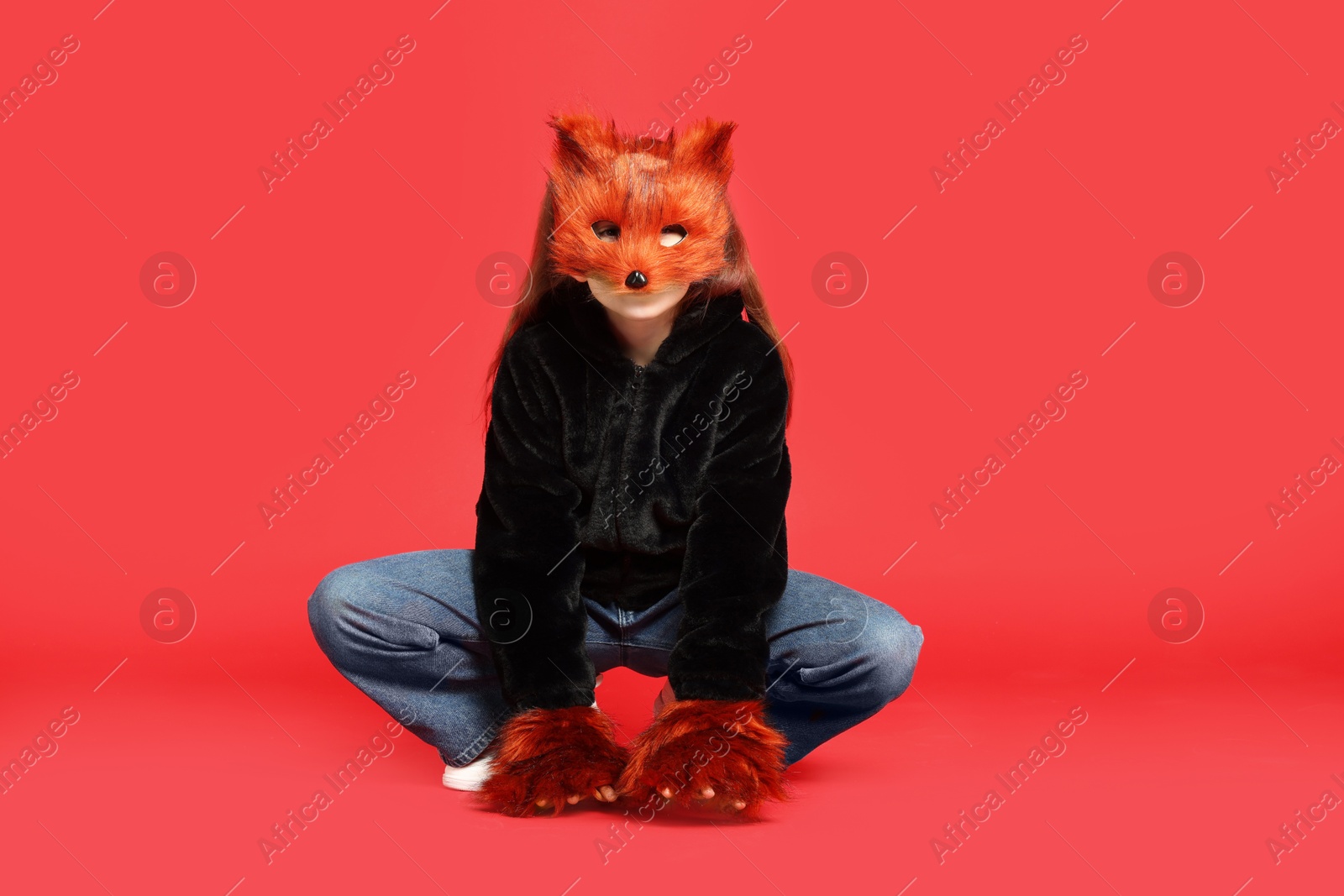 Photo of Quadrobics. Girl wearing fox mask and gloves on red background