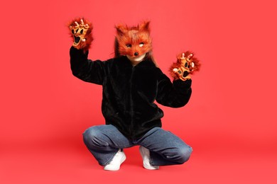 Photo of Quadrobics. Girl wearing fox mask and gloves on red background