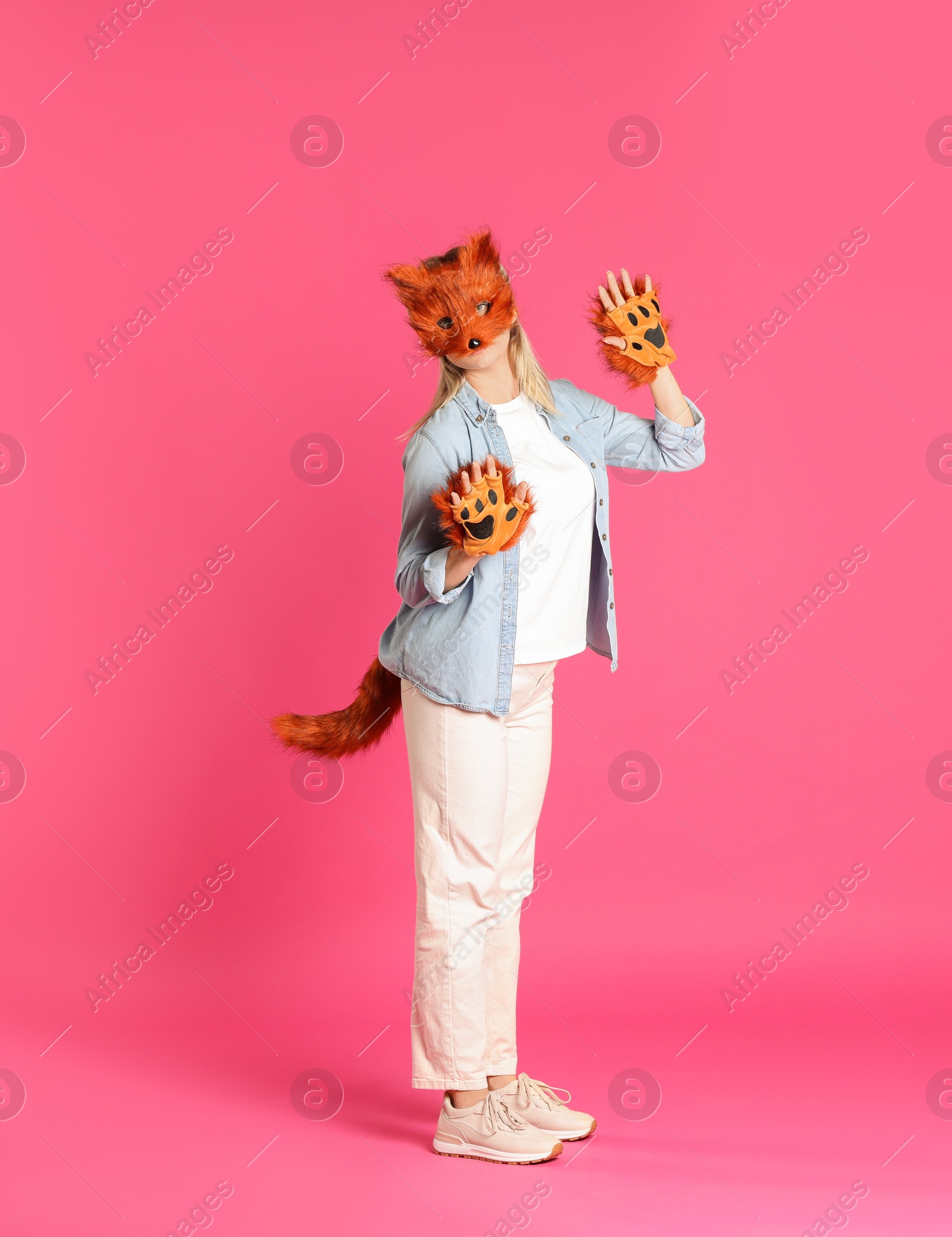 Photo of Quadrobics. Woman wearing fox mask, gloves and tail on pink background