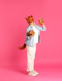 Photo of Quadrobics. Woman wearing fox mask, gloves and tail on pink background