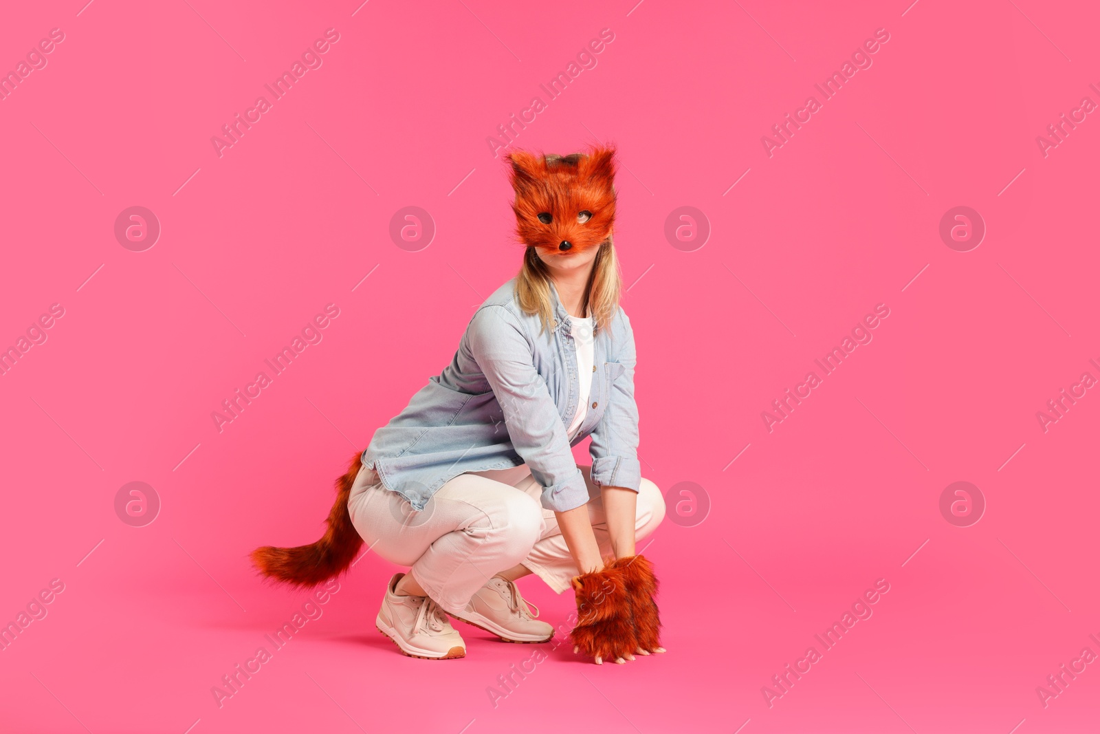 Photo of Quadrobics. Woman wearing fox mask, gloves and tail on pink background