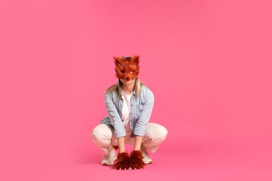 Photo of Quadrobics. Woman wearing fox mask and gloves pink background