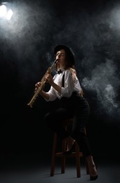 Photo of Musician playing soprano saxophone on dark background with smoke