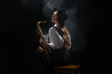 Photo of Professional musician playing saxophone on dark background with smoke