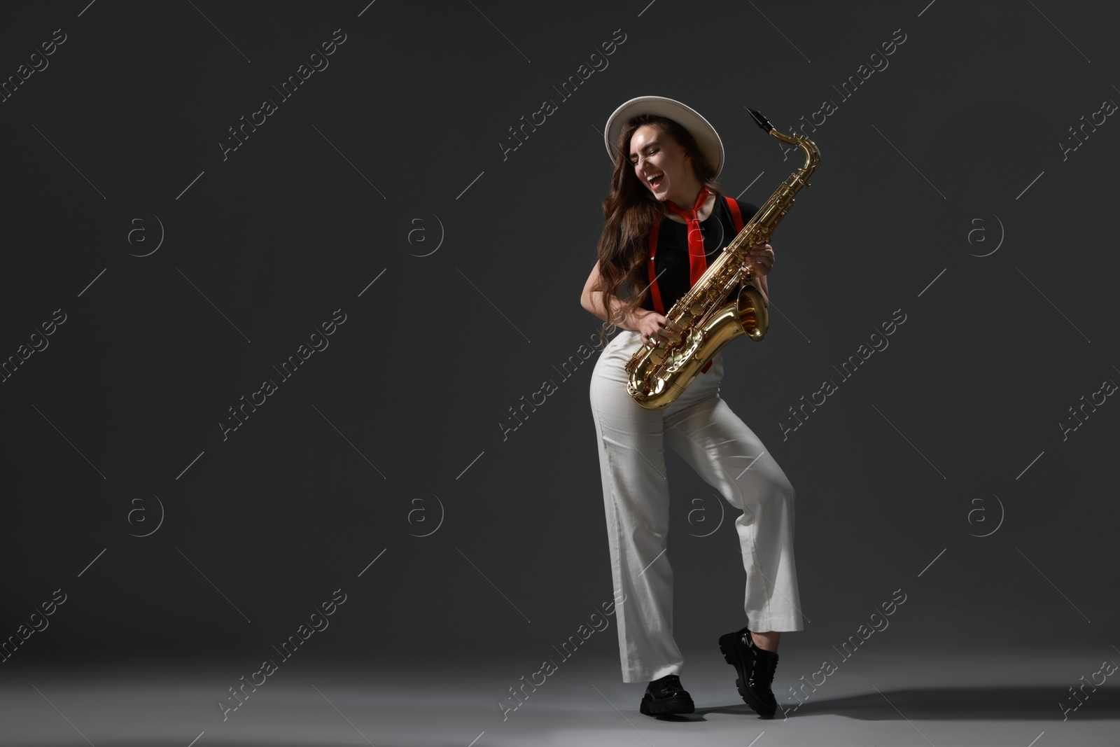 Photo of Professional musician with saxophone on grey background. Space for text