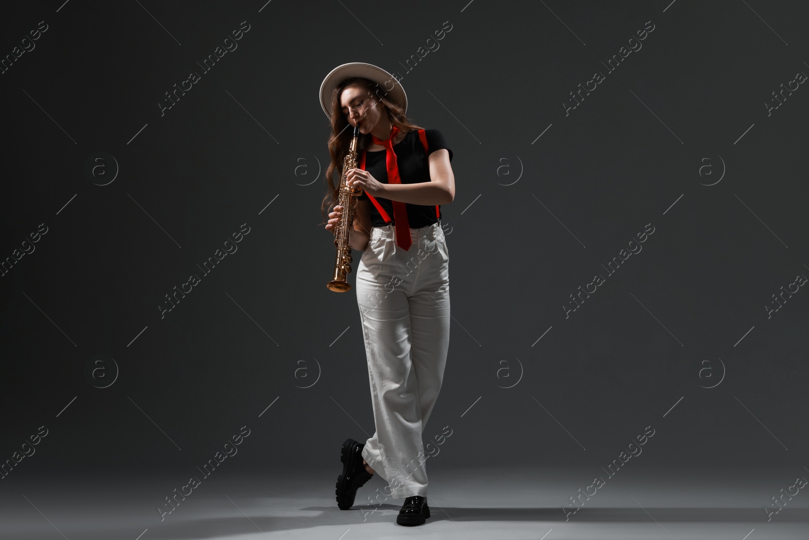 Photo of Musician playing soprano saxophone on grey background