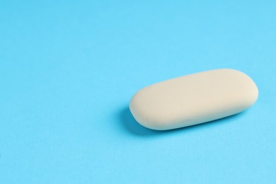 Photo of One eraser on light blue background, closeup. Space for text