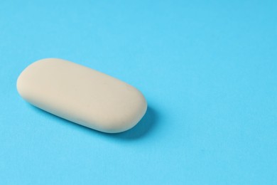 One eraser on light blue background, closeup. Space for text