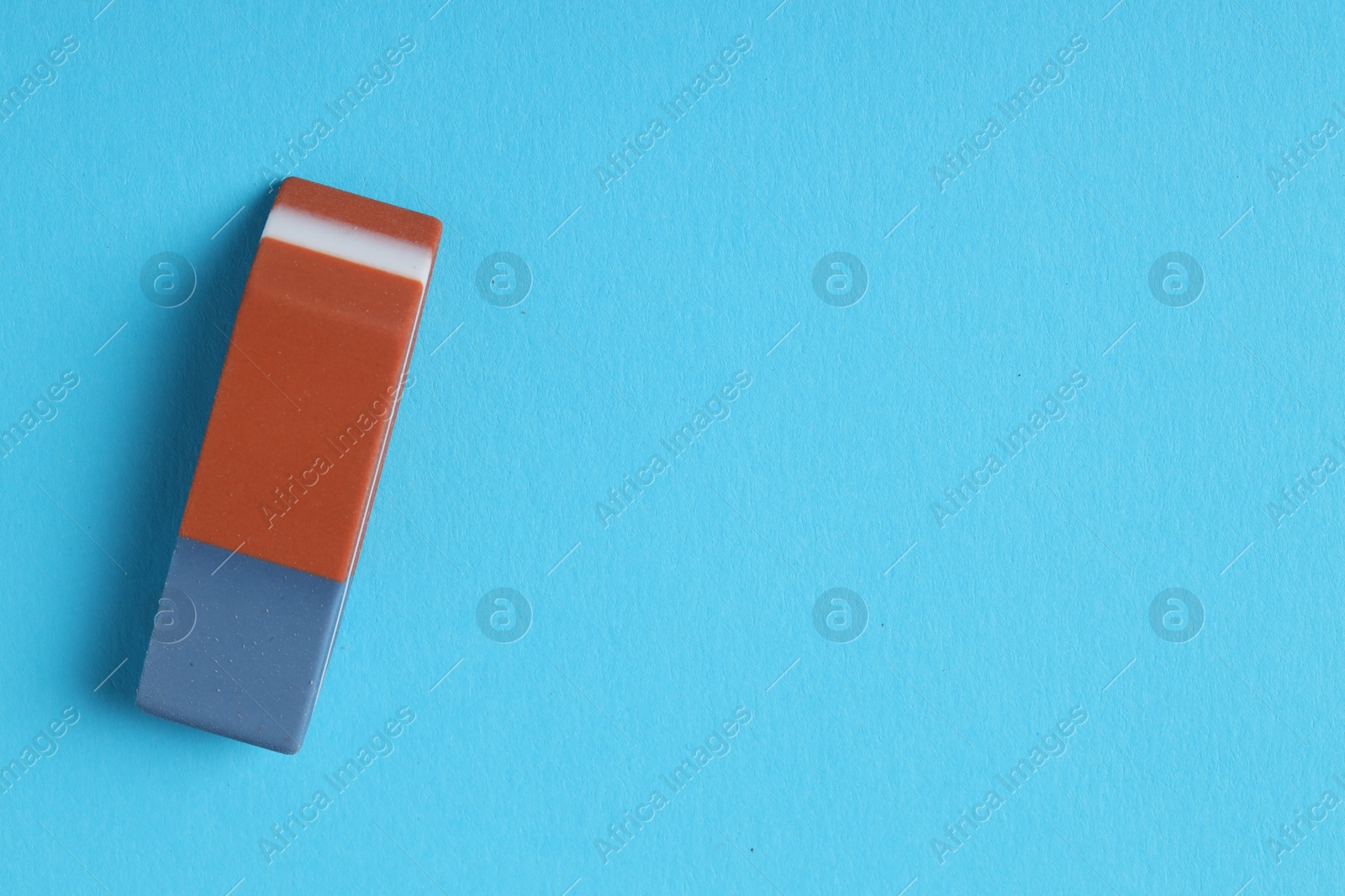 Photo of One eraser on light blue background, top view. Space for text