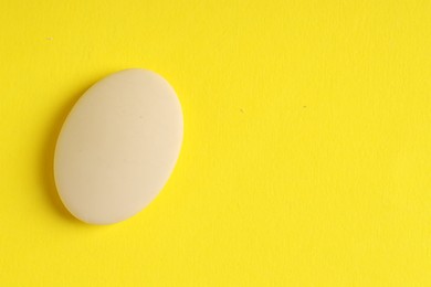 Photo of One eraser on yellow background, top view. Space for text