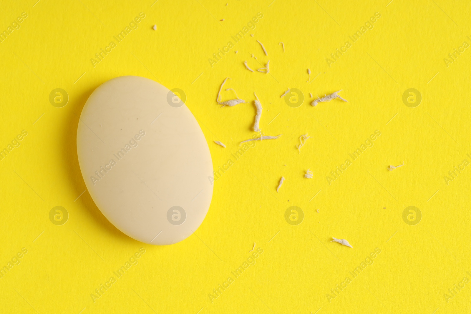 Photo of One eraser and scraps on yellow background, top view