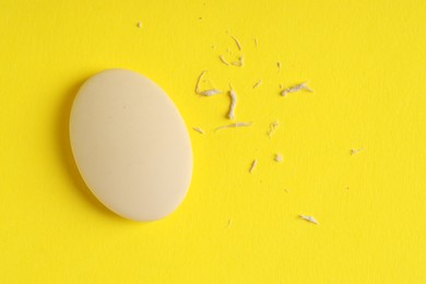 Photo of One eraser and scraps on yellow background, top view