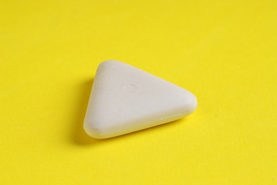 Photo of One eraser on yellow background, closeup view