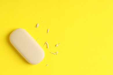 Photo of One eraser and scraps on yellow background, top view. Space for text