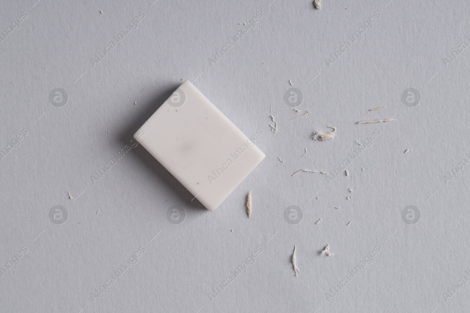 Photo of One eraser and scraps on grey background, top view