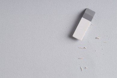 Photo of One eraser and scraps on grey background, top view. Space for text