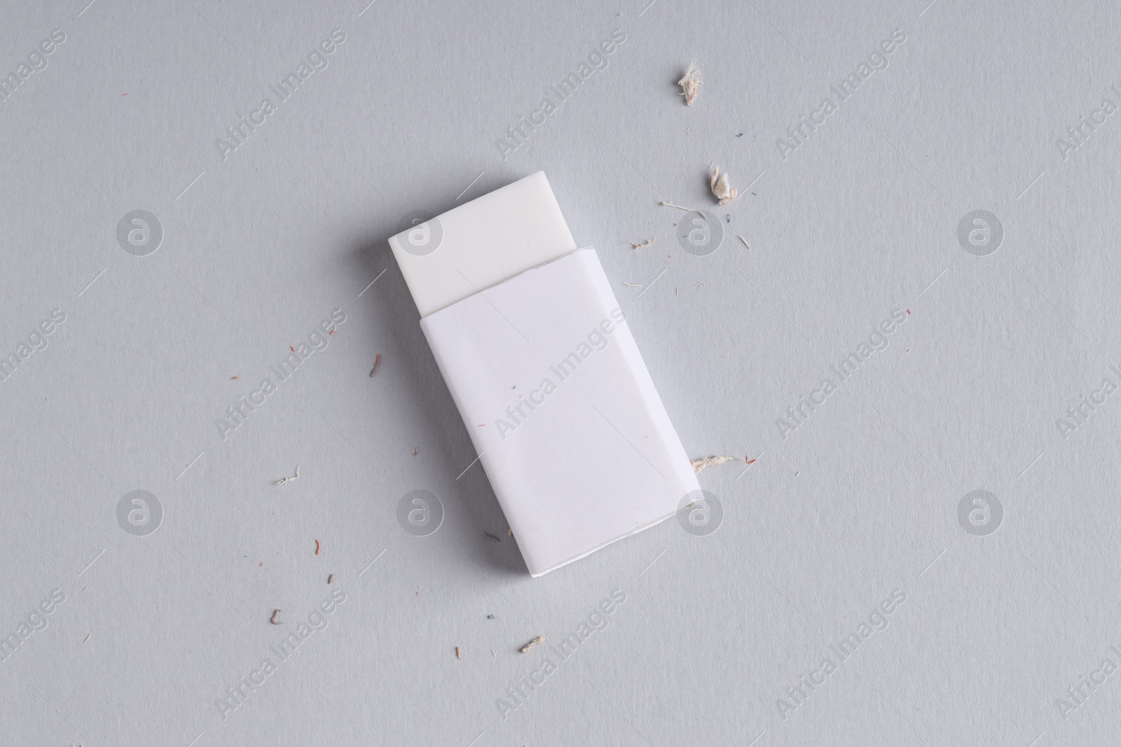 Photo of One eraser and scraps on grey background, top view