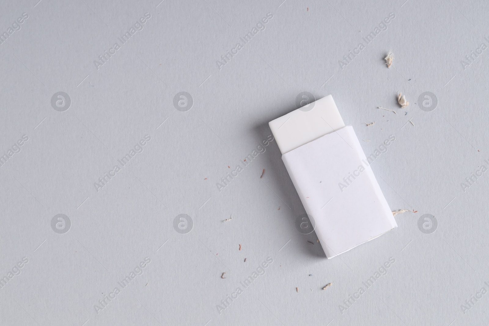 Photo of One eraser and scraps on grey background, top view. Space for text