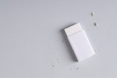 Photo of One eraser and scraps on grey background, top view. Space for text