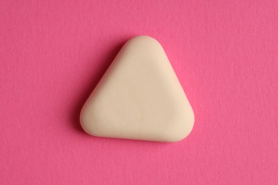 Photo of One eraser on pink background, top view