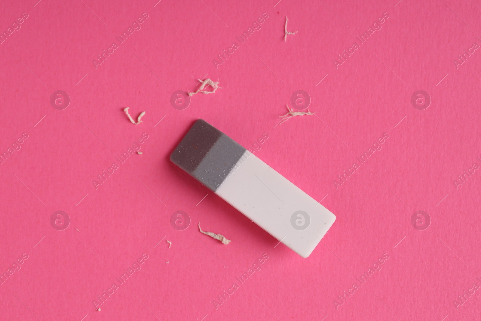 Photo of One eraser and scraps on pink background, top view